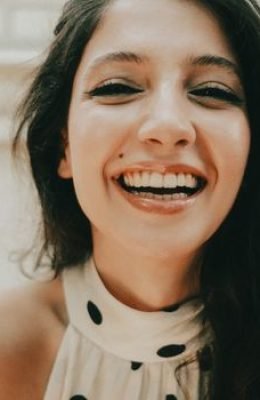 Young woman with a joyful expression and bright smile indoors. Close-up portrait.
