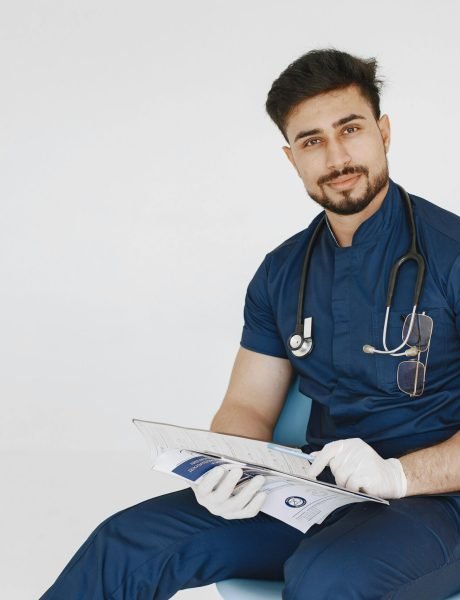 pexels-photo-5888168-5888168-1 Young male doctor in blue scrubs reviewing medical records with a confident smile.